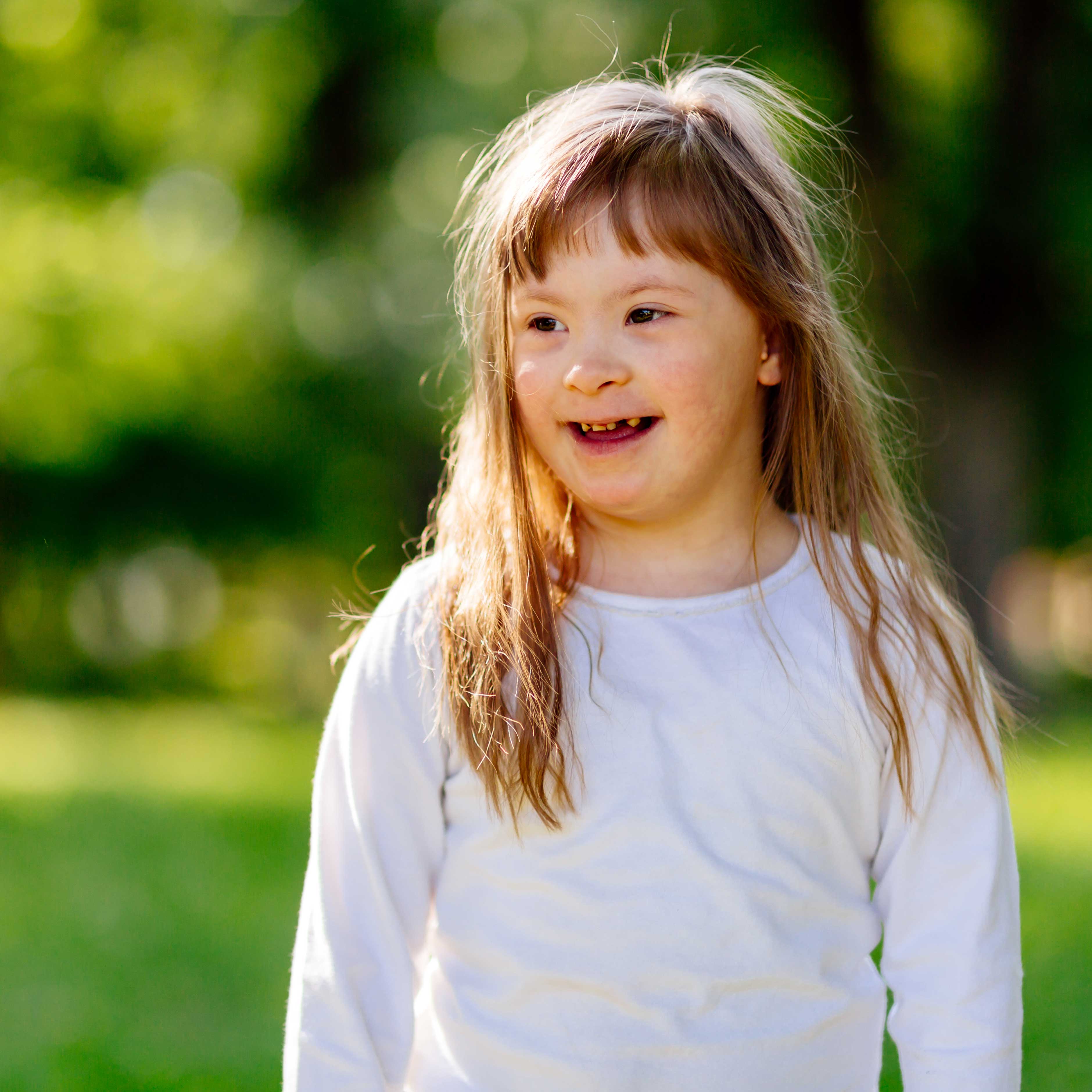 Happy child with down sydrome smiling outdoors